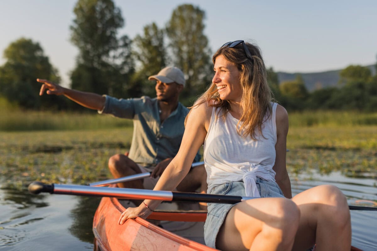 Couple canoeing on calm lake water at sunset enjoying the tranquility of nature